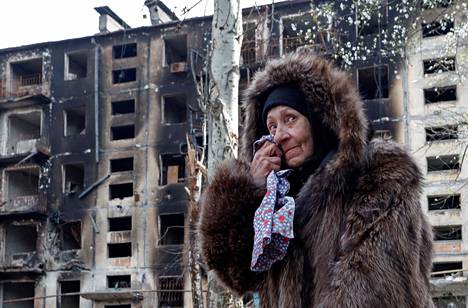 Mariupolilainen nainen pyyhkäisi poskeaan tuhoutuneen kerrostalon luona sunnuntaina 17. huhtikuuta.