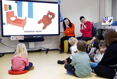 Katri Kunnas ja Sarah Goncalves laulattavat esikoulun pienryhmän lapsia Rauman Pohjoiskehän koulussa, joka on myös Goncalvesin työpaikka. Kuvassa heidän kehittämänsä Kielinuppu-menetelmän laulun aiheena on Nallen koti. Videon kuvitus tukee sanojen oppimista. 