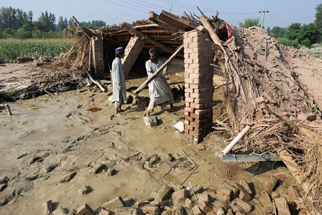 Miehet tulvissa tuhoutuneen talonsa raunioissa Nowsherassa 30. elokuuta.