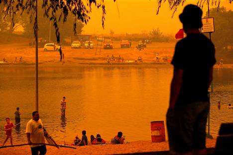 Ihmiset kävivät uimassa Renaicossa Araucanian alueella metsäpalojen värjätessä maiseman kellertäväksi.
