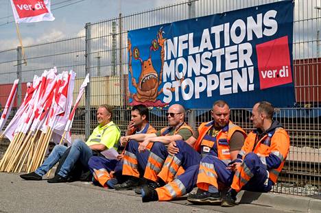 Lakossa olevat työntekijät istuvat inflaation hillitsemistä vaativan kyltin edessä Hampurissa Saksassa 9. kesäkuuta 2022.