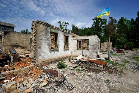 Ukrainan lippu liehuu pommituksissa tuhoutuneen talon vieressä Moshchunin kylässä Kiovan alueella.