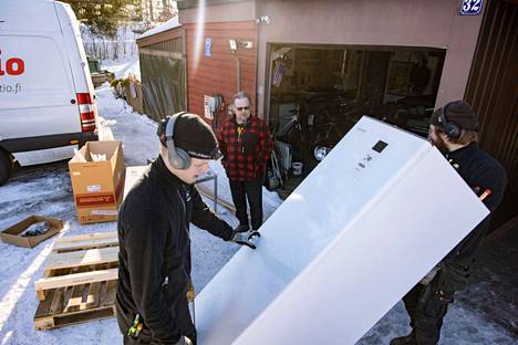 Omakotiasujat parantavat talojensa energiatehokkuutta jo nyt. Kuva talvelta 2022, kun Mika Ahonen vaihtoi öljykattilan ilma-vesi-lämpöpumppuun. Pumpun sisäyksikköä kantamassa Veikko Lahti ja Elmeri Lampela.