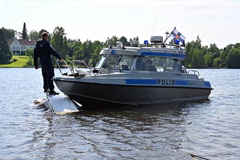 Lasikuituvene uhkasi upota Pyhäjärvellä Viikinsaaren länsipuolella. Kuvassa poliisivene tutkii lähes uponnutta, Pereensaaren rantaan tuotua venettä.