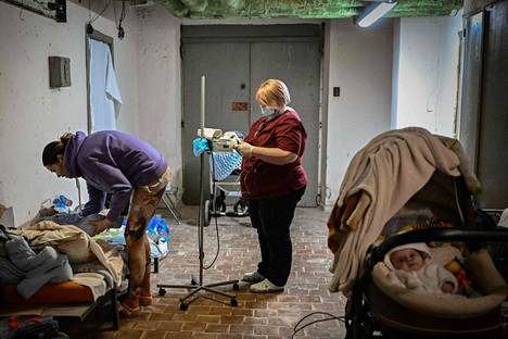 Hoitaja tarkasti pienen lapsen vointia kellariin siirretyissä ”sairaalatiloissa” Ukrainan pääkaupungissa Kiovassa maanantaina. 