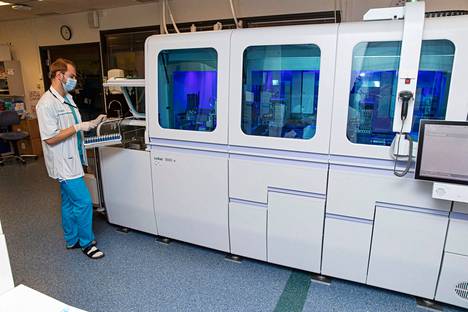 4. joulukuuta 2020 otetussa kuvassa analysoidaan koronatestejä Fimlabin laboratoriossa. Bioanalyytikko-opiskelija Otso Kakko laittoi telineessä olevat näyteputket 94:n putken erässä sinistä valoa hohtavaan analyysikoneeseen.
