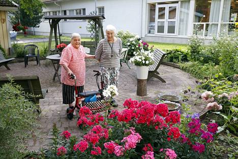 Eini Mattila ja Anja Nyman viihtyvät kerrostalonsa kukoistavassa pihassa, jota hoidetaan asukasvoimin. 