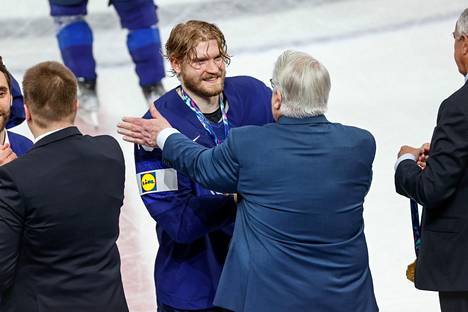 Kuva on kevään 2022 jääkiekon MM-finaalista. Kiekkolegenda Kalervo Kummola onnittelee tuoretta maailmanmestaria Joel Armiaa.