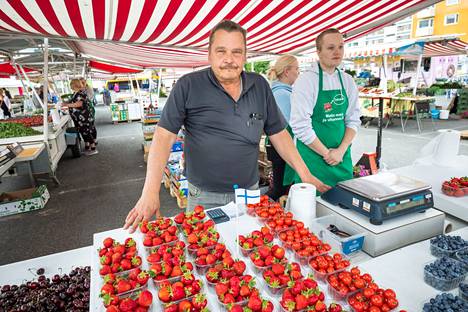 Matin marja ja vihannes-kojun yrittäjä Matti Valtakivi (keskellä) kertoo, että mansikoiden hinnat voivat tippua juhannuksen jälkeen, sillä mansikoita saadaan silloin enemmän myyntiin.