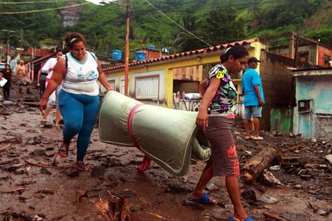Asukkaat keräsivät omaisuuttaan maanvyöryn jälkeen Puerto La Cruzissa perjantaina.