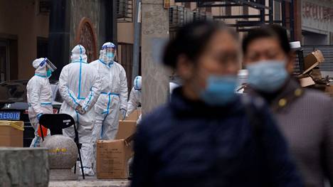 Asukkaat kävelivät suojavarusteisten työntekijöiden ohitse Kiinan Pekingissä perjantaina 18. marraskuuta.