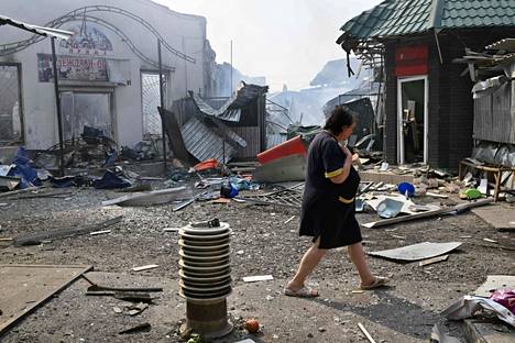 Nainen ohittaa tuhoutuneita kauppoja paikallisella torilla raketti-iskun jälkeen Ukrainan Slovjanskissa 3. heinäkuuta 2022.