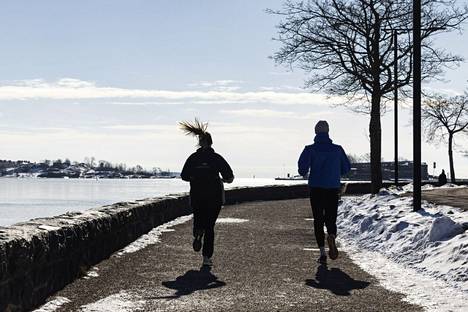 Ulkoilijoita juoksemassa aurinkoisena pakkaspäivänä Helsingissä Etelärannassa maaliskuussa.