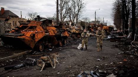 Ukrainalaissotilaita kävelemässä tuhottujen venäläistankkien ja sotilasajoneuvojen ohi Butšassa.