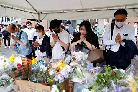 Sadat ihmiset toivat uutistoimistojen mukaan kukkia Aben surmapaikalle lauantaina.