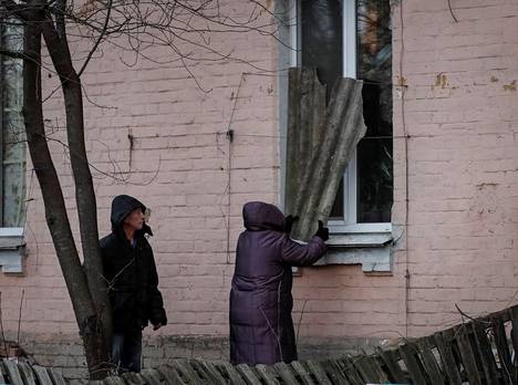Nainen suojaa talonsa ikkunoita pommituksen varalta Kiovan päärautatieaseman lähellä.