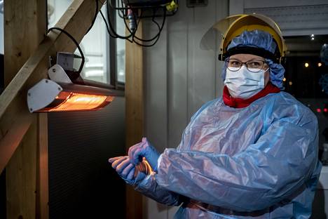 Sairaanhoitaja Anu Seppä lämmittelee käsiään lämpölampun alla koronatestauspisteellä Järvenpäässä. Hän on ottanut pandemian aikana jo 25 000 testiä. Testit otetaan ulkona talvellakin.