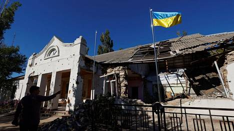 Ukrainan lippu liehui pahoja vahinkoja kärsineen rakennuksen edustalla Etelä-Ukrainan Mykolajivin alueella sijaitsevassa kylässä tiistaina 18. lokakuuta.