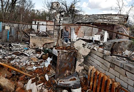 Olexandr Tšernenko, 54, esittelee naapurinsa tuhoutunutta taloa. Tšernenkon mukaan naapuri kuoli ammuksen sirpaleeseen.
