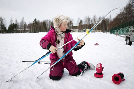 Ella Jokinen keskittyy laittamaan suksia nippuun. Huppu on muuten loistava jemmapaikka pidikkeille hiihdon ajaksi.