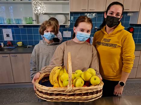 Koulun aamiaisella on tarjolla muun muassa omenaa ja banaania, esittelevät oppilaskunnan edustajat, seitsemäsluokkalaiset Lumi Heinisuo ja Aleksi Linnikko. Oikealla koulunkäynninohjaaja Emma Ståhl.