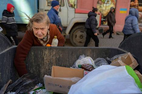Nainen etsi ruokaa roska-astiasta Odessan keskustassa. 