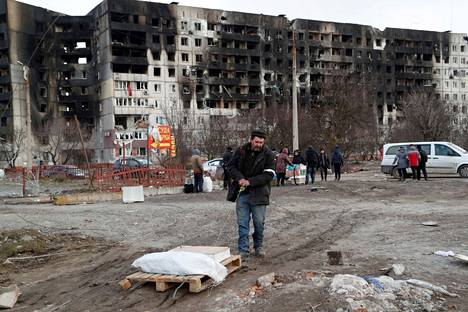Ihmisiä kokoontui pommituksissa tuhoutuneiden talojen läheisyyteen Mariupolissa Ukrainassa. Kuva on otettu torstaina 17. maaliskuuta.