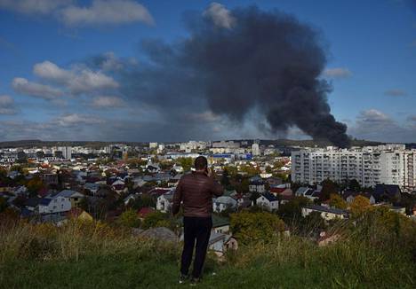Mies katseli kukkulalta venäläisten ohjusten aiheuttamia savupatsaita Lvivin kaupungissa tiistaina.