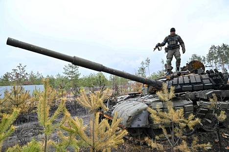 Ukrainalainen sotilas seisoo tuhotun venäläisen panssarivaunun päällä pääkaupunki Kiovan lähistöllä.