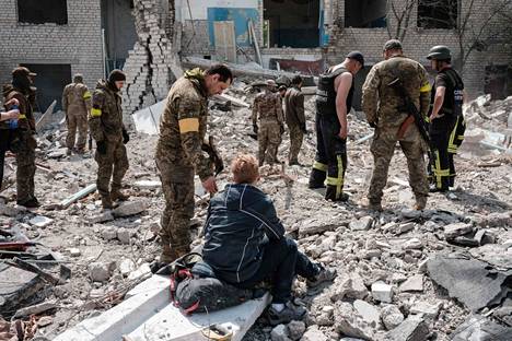 Maassa istuva nainen istuu maassa ja uskoo, että hänen miehensä on jäänyt pommituksessa tuhoutuneen koulun raunioiden alle. Hänen vieressään on Ukrainan armeijan sotilaita. Pommituksissa tuhoutunut koulu sijaitsee Sydorovessa itä-Ukrainassa. Kuva on otettu 17. toukokuuta. 