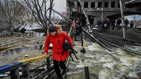 Kiovalainen kantoi koiraansa turvaan tuhoutuneen sillan vieressä Kiovan pohjoispuolella tiistaina 1. maaliskuuta.