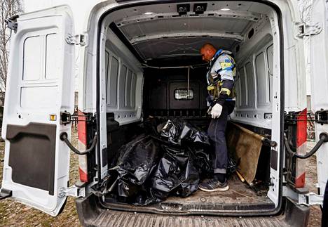 Vapaaehtoinen purkamassa pakettiautosta siviilien ruumiita sisältäviä ruumispusseja Butšassa.