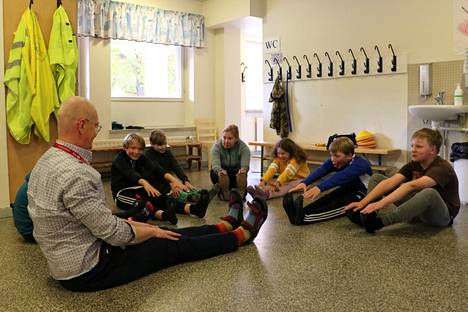 Viidesluokkalaisten Move-testin lomassa kokeiltiin, saako suorilla jaloilla varpaista kiinni. Luokanopettaja Sari Korhonen (keskellä) opettaa myös liikuntaa sekä ala- että yläkoululaisille. 