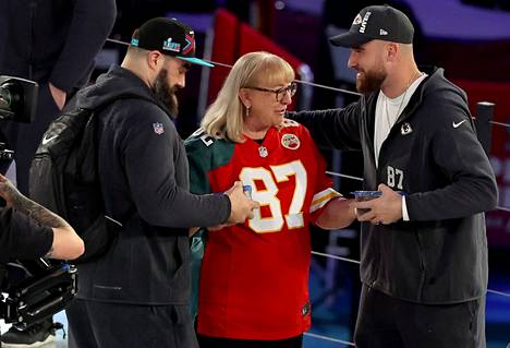 Donna Kelce yllätti poikansa Jasonin (vas.) ja Travisin Super Bowlin mediapäivänä tuomalla molemmille keksejä. Donna Kelcellä oli päällään pelipaita, joka on etupuolelta Chiefsin ja takaa Eaglesin.