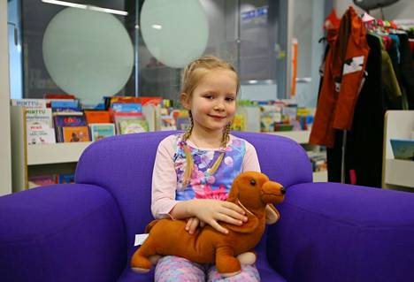 Kuusivuotias Elisabeth Holland pääsi hypistelemään uusia välineitä kirjaston lastenosastolla. Hänellä on sylissään reilun kahden kilon painoinen terapiakoira, joka auttaa rauhoittumaan ja keskittymään.