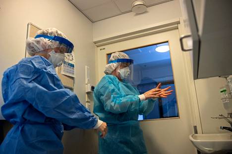 Sairaanhoitajat Jenna Himanen (vasemmalla) ja Eliina Lampila pukivat varusteita koronapotilaan hoitoa varten Tays Hatanpään infektioyksikössä maanantaina 29. marraskuuta.