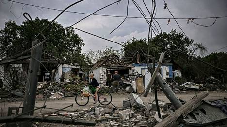 Tyttö ajoi polkupyörällä pahoin tuhoutuneiden rakennusten ohitse Itä-Ukrainanan Donetskin alueella sijaitsevassa Dobropilljan kaupungissa 15. kesäkuuta.
