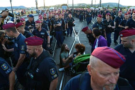 Poliisit piirittävät Margit-sillan tiellä istuvia mielenosoittajia Budapestissa keskiviikkona 12. heinäkuuta. Silta on yksi Budapestin vilkkaiten liikennöidyistä silloista. 