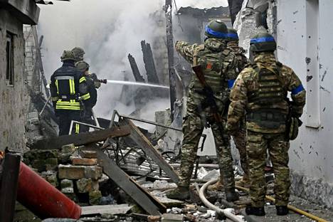 Ukrainalaiset pelastajat vaurioituneessa asuinrakennuksessa Hersonissa sunnuntaina. 