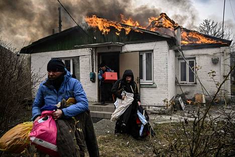 Ihmiset kantoivat tavaroita tuleen syttyneestä talosta Irpinissä 4. maaliskuuta.