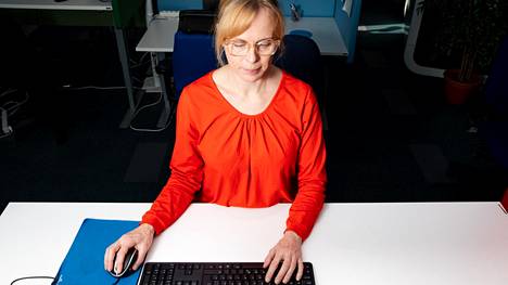 Työterveyslaitoksen erityisasiantuntija Elina Östring näyttää oikeanlaisia työskentelyasentoja tietokoneen ääressä. Käsien pitää saada tukea pöytätasosta.