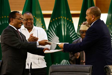 Etiopian hallituksen edustaja Redwan Hussein Rameto (vas.) ja Tigrayn edustaja Getachew Reda (oik.) vaihtoivat asiakirjoja rauhansopimuksen allekirjoittamisen jälkeen keskiviikkona.