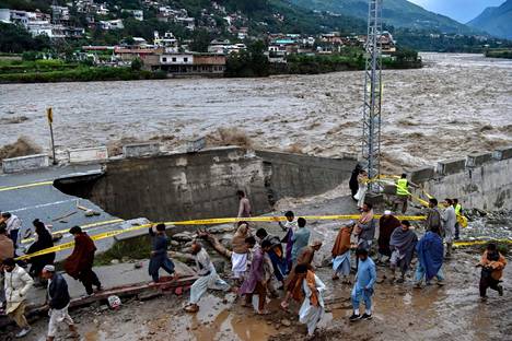 Ihmiset kulkevat tulvan vaurioittaman tien ohi Swatin laaksossa Luoteis-Pakistanissa 27.elokuuta 2022. 