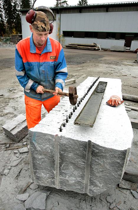Kiviseppä Kimmo Vesterinen saa graniittipaaden lohkemaan pienten kiilojen avulla.