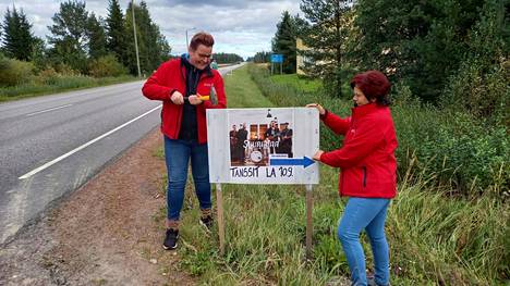 PULSilaiset Paula Muukkonen ja Ulla Kerola laittamassa lauantain tanssien mainoskylttiä tien varteen.