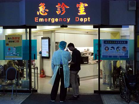 Lääkintähenkilökunnan jäsen mittasi kuumetta potilaalta Taiwanin pääkaupungissa Taipeissa sijaitsevan sairaalan päivystyksessä perjantaina. Korkea kuume on yksi koronaviruksen aiheuttamista oireista.