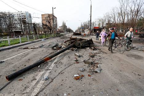 Ihmisiä käveli tuhoutuneen tankin osien ohi ohi Mariupolin kaupungissa Ukrainassa 17. huhtikuuta.
