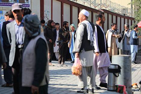 Talebanin taistelijoita seisoi vartiossa, kun ihmiset kerääntyivät etsimään sukulaisiaan sairaala ulkopuolella Kabulissa pommi-iskun jälkeen 30. syyskuuta. 