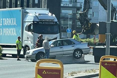 Vanhahko Mercedes Benz oli jäänyt jumiin työmaa-aidan päälle. Poliisi ohjasi ohi kulkevaa liikennettä sillä aikaa, kun kaivinkone auttoi autoa pois pinteestä.
