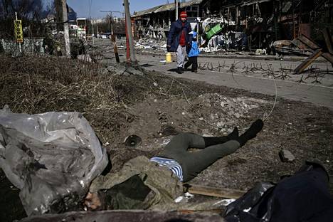 Paikalliset asukkaat kulkivat ruumin ohi Irpinissä 10. maaliskuuta. Kaduilla Ukrainan eri kaupungeissa on edelleen paljon peittämättömiä ruumiita, sillä hautaaminen ei ole mahdollista pommitusten keskellä. Osa ruumista on peitetty joukkohautoihin, kertoivat ukrainalaisviranomaiset lauantaina. 
